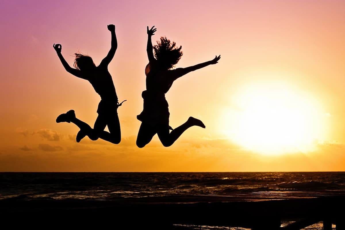 2 personnes sautant en l'air de joie, au coucher du soleil