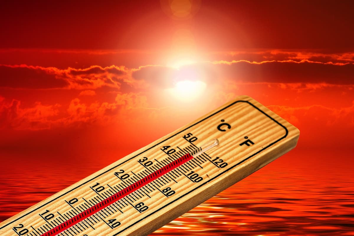 Thermomètre avec température élevée sur un paysage de mer, au soleil couchant, rougeoyant